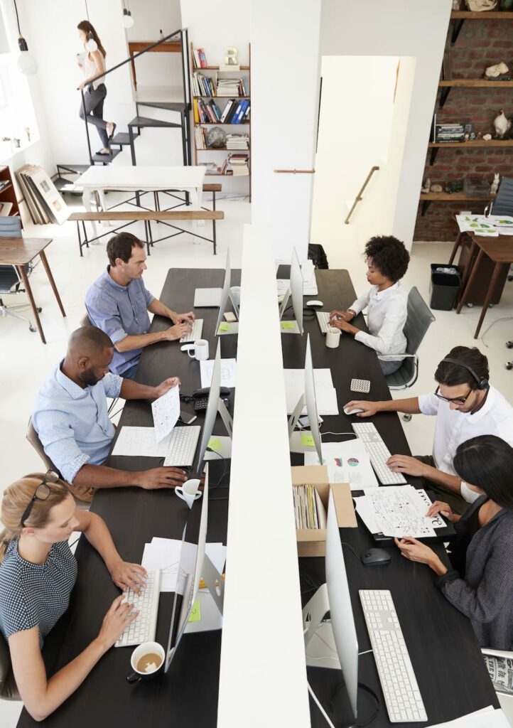 colleagues working at a busy open plan office PQMUBW3